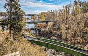 A green pedestrian bridge over a river with a building in the background.