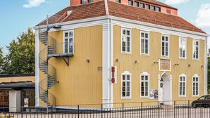 A yellow building with a red roof, a staircase, and a sign indicating a business. - Amazing home in åsensbruk with WiFi (Åsensbruk)
