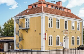 Ein gelbes Gebäude mit rotem Dach, einer Treppe und einem Schild, das auf ein Geschäft hinweist.