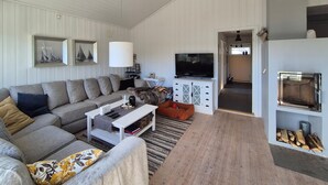 A living room with a sectional sofa, a flat-screen TV, a fireplace, and a dining area. - Pet friendly home in Mosterhamn with sauna (Mosterhamn)
