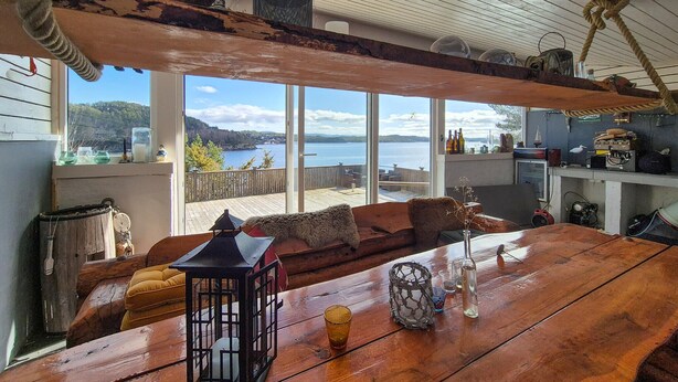 A cozy room with a wooden table, a lantern, and a view of a lake. - Pet friendly home in Mosterhamn with sauna (Mosterhamn)