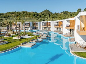 A modern resort with multiple swimming pools, sun loungers, and a lush green landscape in the background. - Anna Island (Pefkochori)