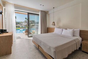 A hotel room with a large bed, a desk, and a view of a swimming pool and palm trees. - Anna Island (Pefkochori)