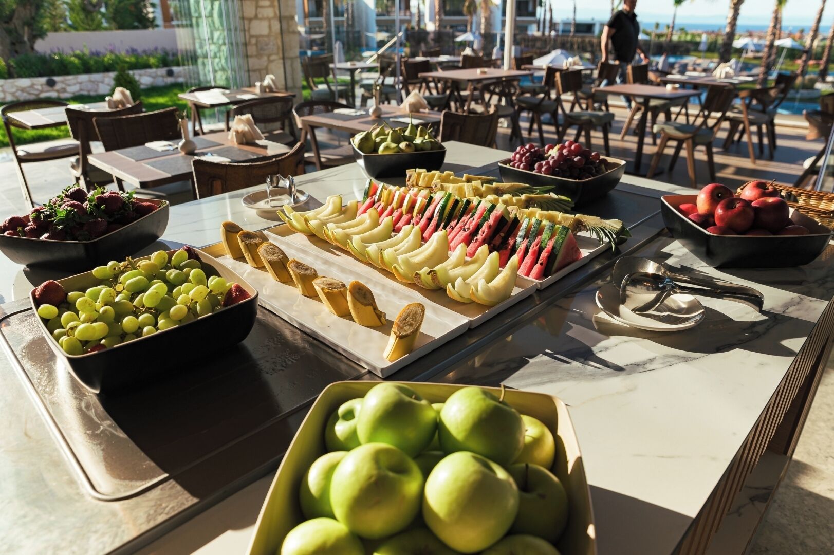 A buffet table with various fruits and a bowl of green apples.