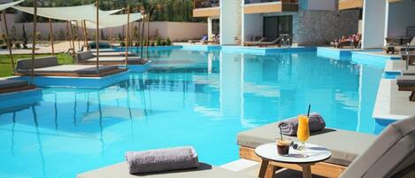 A modern pool area with lounge chairs and a table with a drink and towel.