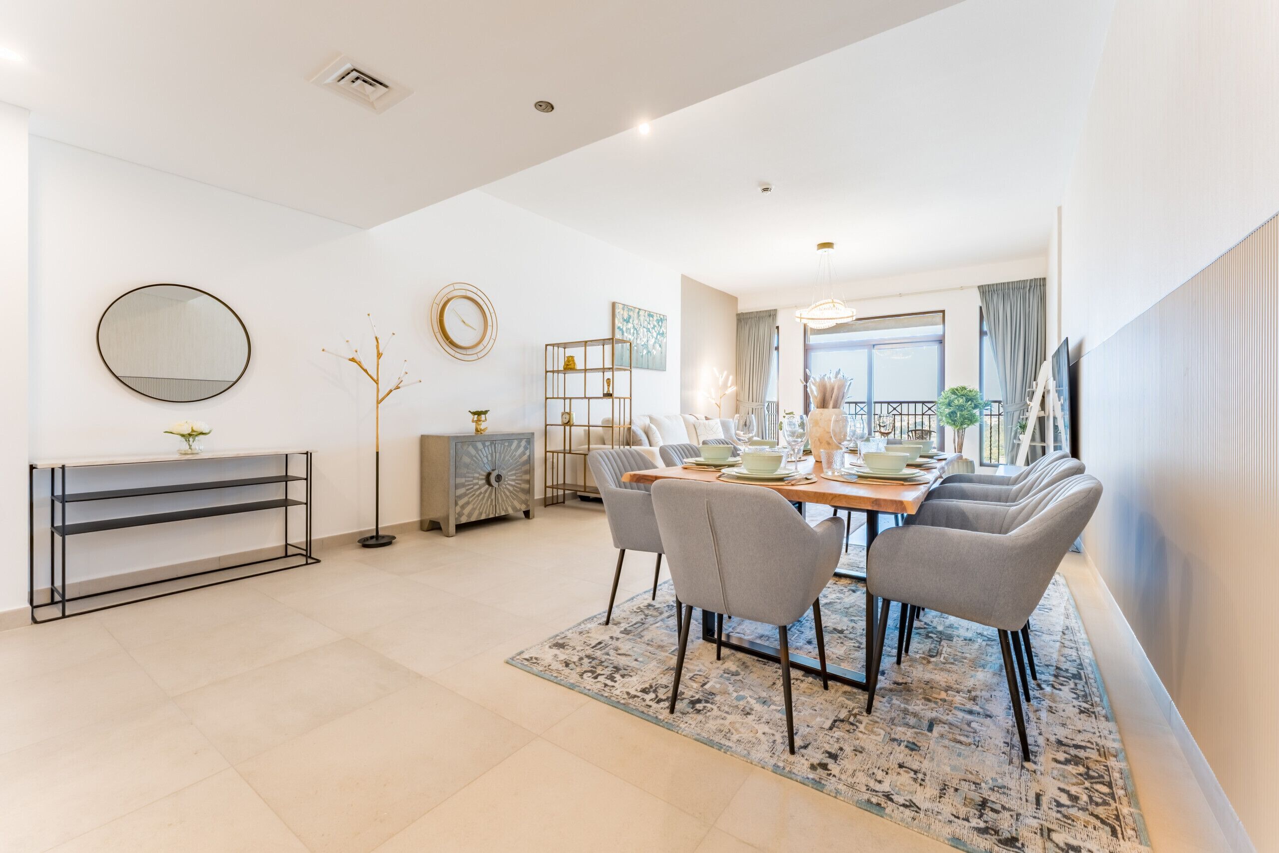 Un espace repas moderne avec une table ronde, des chaises grises et un tapis à motifs.