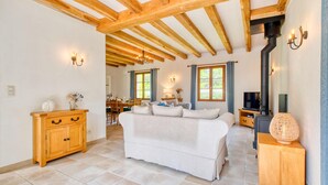 A cozy living room with a sofa, wooden beams, a fireplace, and a dining area. - Gorgeous home in Trémolat (Trémolat)