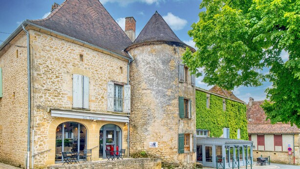 A stone building with a tower, a café with outdoor seating, and a covered outdoor area. - Gorgeous home in Trémolat (Trémolat)