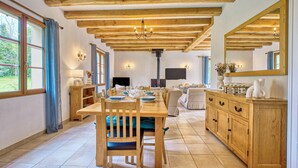 A spacious room with a wooden dining table, chairs, a sofa, and a cabinet. - Gorgeous home in Trémolat (Trémolat)