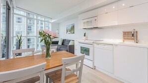 A modern kitchen with white cabinets, a dining table with chairs, and a vase of flowers. - 1BR Apartment in Toronto close to CN tower and Rogers Centre (Toronto)