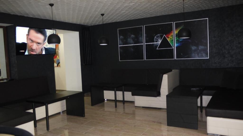 A modern waiting area with black and white furniture, a television screen, and abstract wall art.