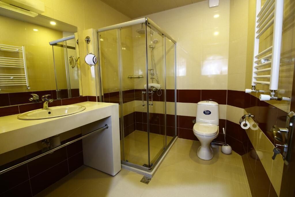 Um banheiro moderno com chuveiro envidraçado, pia, vaso sanitário e espelho.
