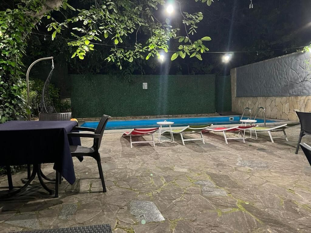 Un espace extérieur aménagé en terrasse, avec une piscine, un revêtement de sol en pierre et du mobilier d’extérieur.