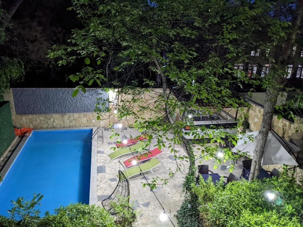A rooftop pool area with a blue pool, lounge chairs, and a stone wall.