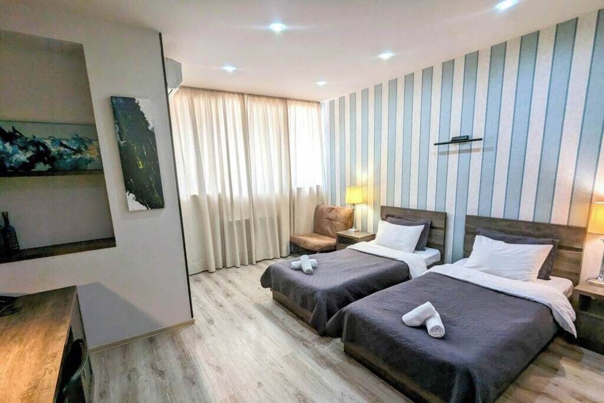 A hotel room with two beds, a desk, a chair, and a TV.