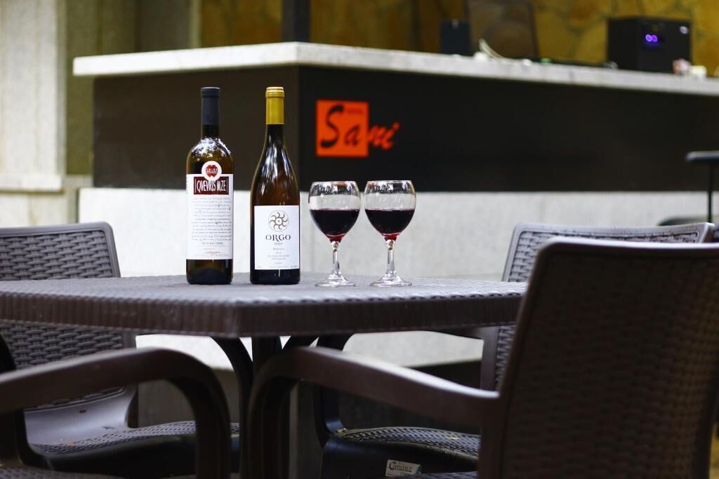 A table with two bottles of wine and two glasses of red wine.