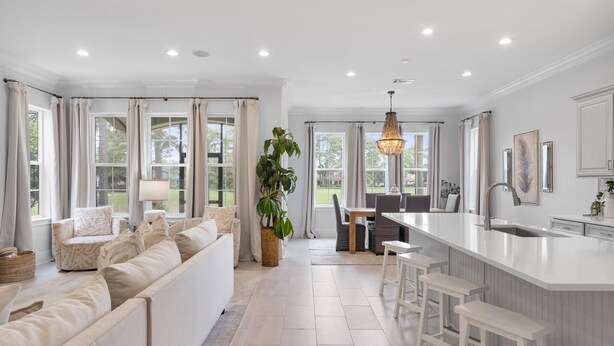 A modern kitchen with a large island, white cabinetry, and a dining area with a table and chairs.
