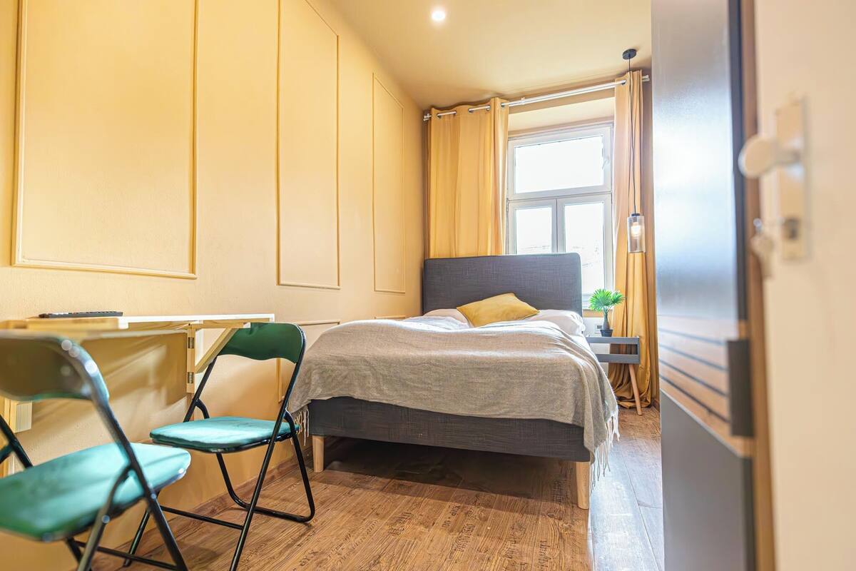 A bedroom with a bed, a desk, and two chairs.