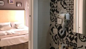 Egy hálószoba, amelyben található egy ágy, egy éjjeliszemélyzet és egy kisebb asztal. A fürdőszobában mosdókagyló, tükör és törölközőtartó van.
