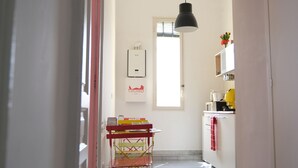 Un corridoio che conduce a una cucina con un cartello 'Cuisine', una finestra e un lampadario.