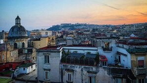 Paesaggio urbano con edifici storici, una cupola imponente e una collina sullo sfondo.