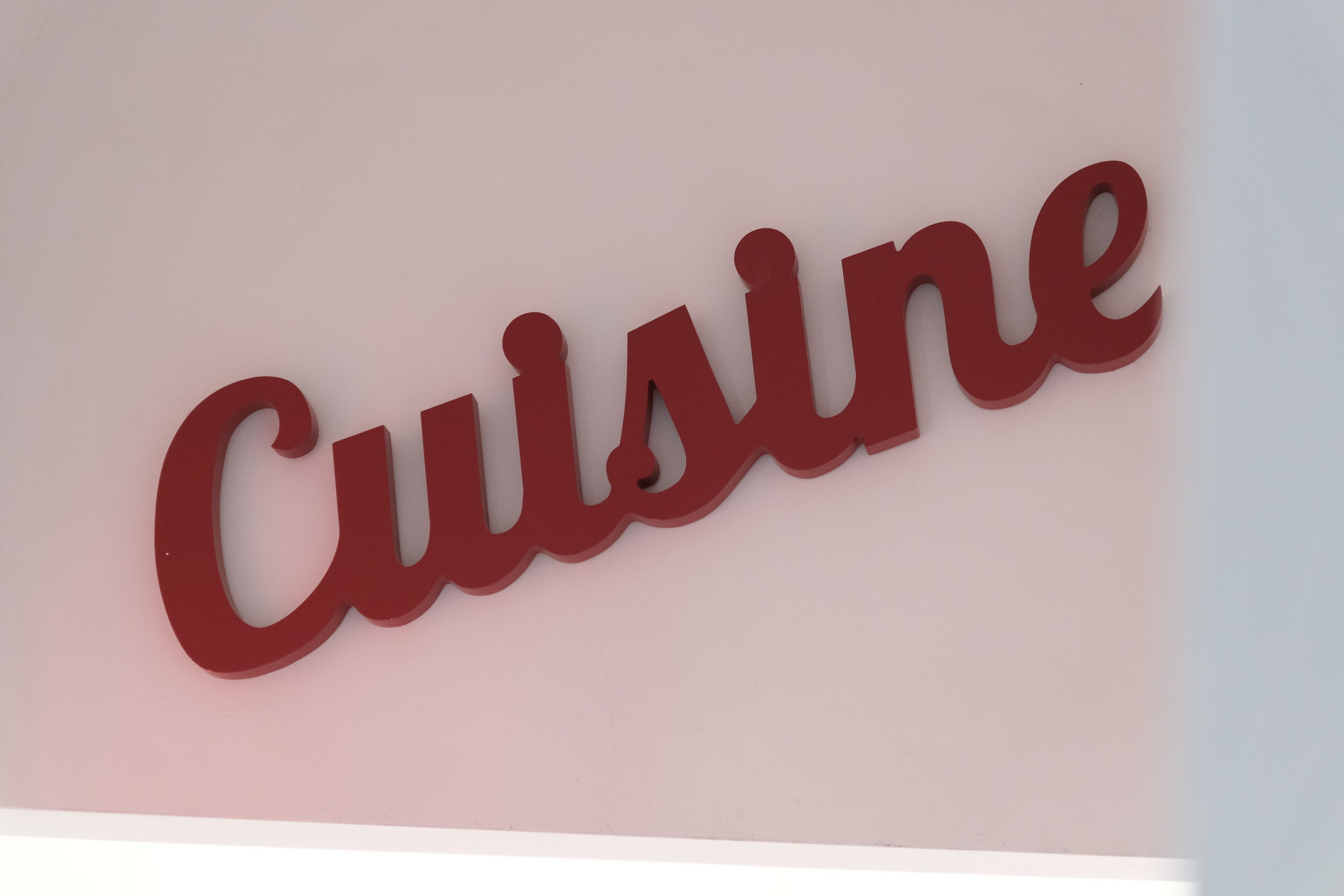 A red sign with the word "Cuisine" on a light pink background.