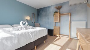 A modern bedroom with a bed, bedside table, and a small wooden shelf. - Coastal Inn - Private Room (Zandvoort)