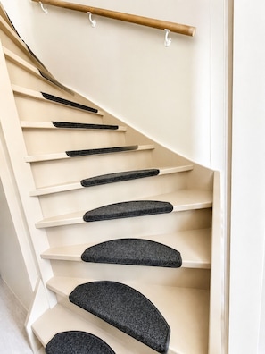 Una escalera curva con peldaños color beige y peldaños antideslizantes negros.