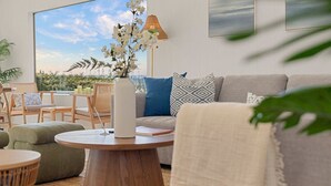 Un salon moderne avec une grande fenêtre, un canapé, une table basse et une lampe.