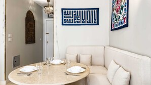 A dining area with a round table, chairs, and a sofa. - Xuru Stays I Authentic Traditions Cozy Stays, 1bdr (Cairo)