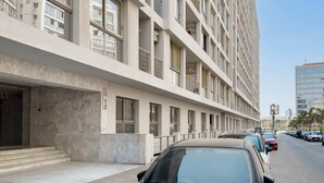 A modern building with a clean facade, large windows, and a parking area with several cars. - Xuru Stays I Authentic Traditions Cozy Stays, 1bdr (Cairo)