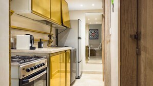A kitchen with a stove, oven, refrigerator, and gold cabinets. - Xuru Stays I Authentic Traditions Cozy Stays, 1bdr (Cairo)
