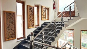 A staircase with a metal railing, wooden decorative panels, and a fire extinguisher on the wall. - Azure Chandertal Regency Hotel And Spa (Manali)
