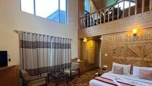 A wooden-floored room with a bed, a sofa, a table, and a chair. - Azure Chandertal Regency Hotel And Spa (Manali)