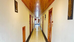 A long, narrow hallway with wooden doors and a polished floor, leading to a bright room at the end. - Azure Chandertal Regency Hotel And Spa (Manali)