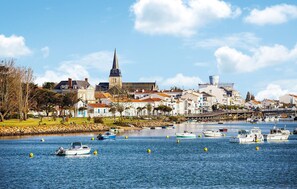 A coastal town with historic buildings, a prominent church tower, and a bridge over the water.