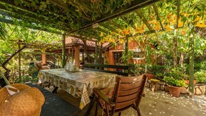 An outdoor dining area with a table set for two, surrounded by potted plants and a pergola structure. - Beautiful apartment in Mandre with house sea view (Mandre)