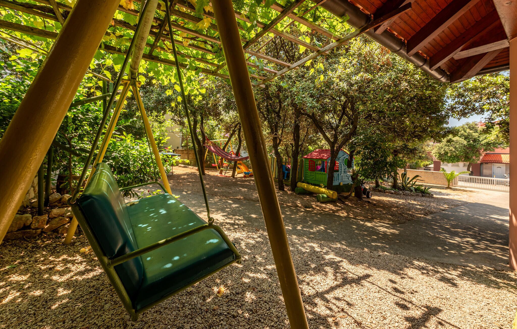 A covered outdoor area with a swing set and a small playhouse.