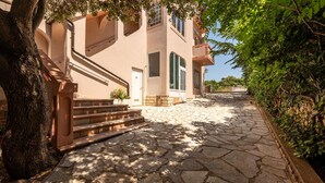 A stone-paved pathway leading to a building with a staircase and a tree on the left. - Beautiful apartment in Mandre with house sea view (Mandre)