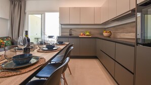 A modern kitchen with a dining area, featuring a large window, built-in cabinets, and a central island with a bowl of fruit. - 3 bedroom lovely apartment in Trappeto (Trappeto)