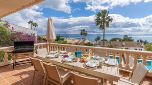Eine Terrasse mit Frühstückstisch, mit Blick auf einen Pool und eine malerische Landschaft aus Meer und Bergen.