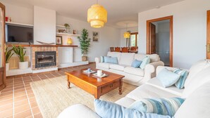 Ein Wohnzimmer mit Kamin, weißen Sofas, einem Holztisch und einem Fernseher.