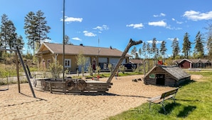 A rustic cabin with a wooden exterior, a small porch, and a dirt path leading to it.