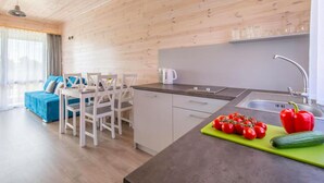 A modern kitchen with wooden cabinetry, a dining area with white chairs, and a red bell pepper on a cutting board. - Stunning home in Krynica Morska with WiFi (Krynica Morska)