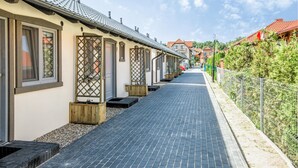 A row of traditional-style buildings with tiled roofs, a paved walkway, and a metal fence on one side. - Stunning home in Krynica Morska with WiFi (Krynica Morska)