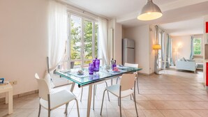 A modern kitchen with a glass dining table, white chairs, and a hanging light fixture. - Cozy home in Capolona (Capolona)