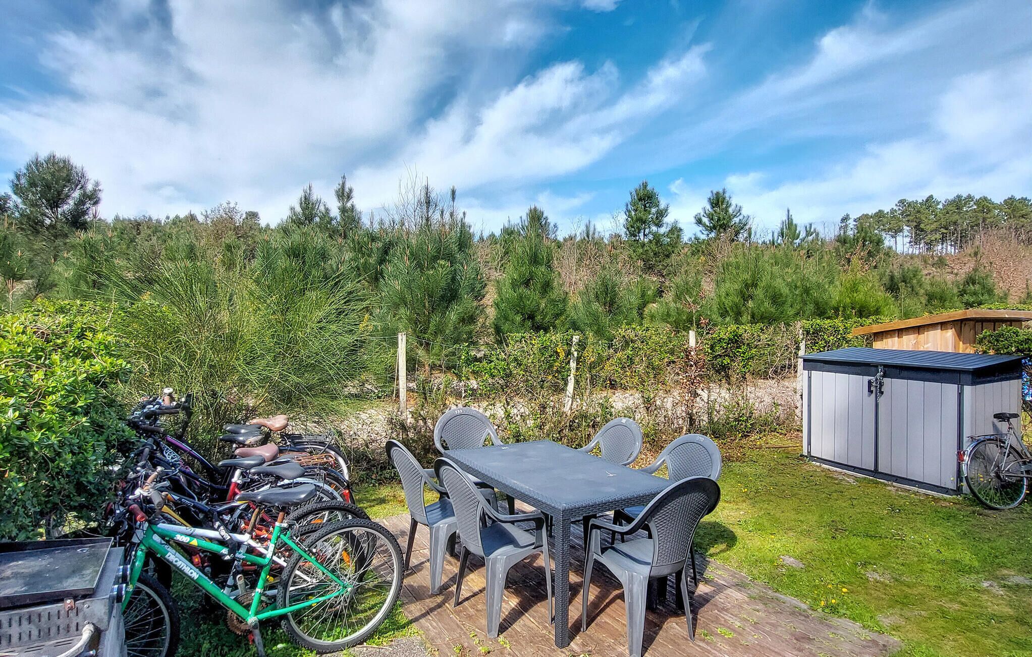 En uteplats med ett bord och stolar, ett cykelställ och ett förråd.