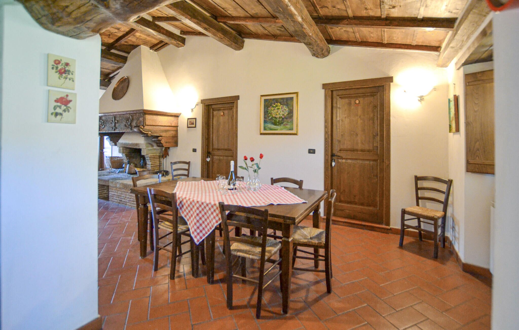 A rustic dining area with a checkered tablecloth, wooden chairs, and a tiled floor.