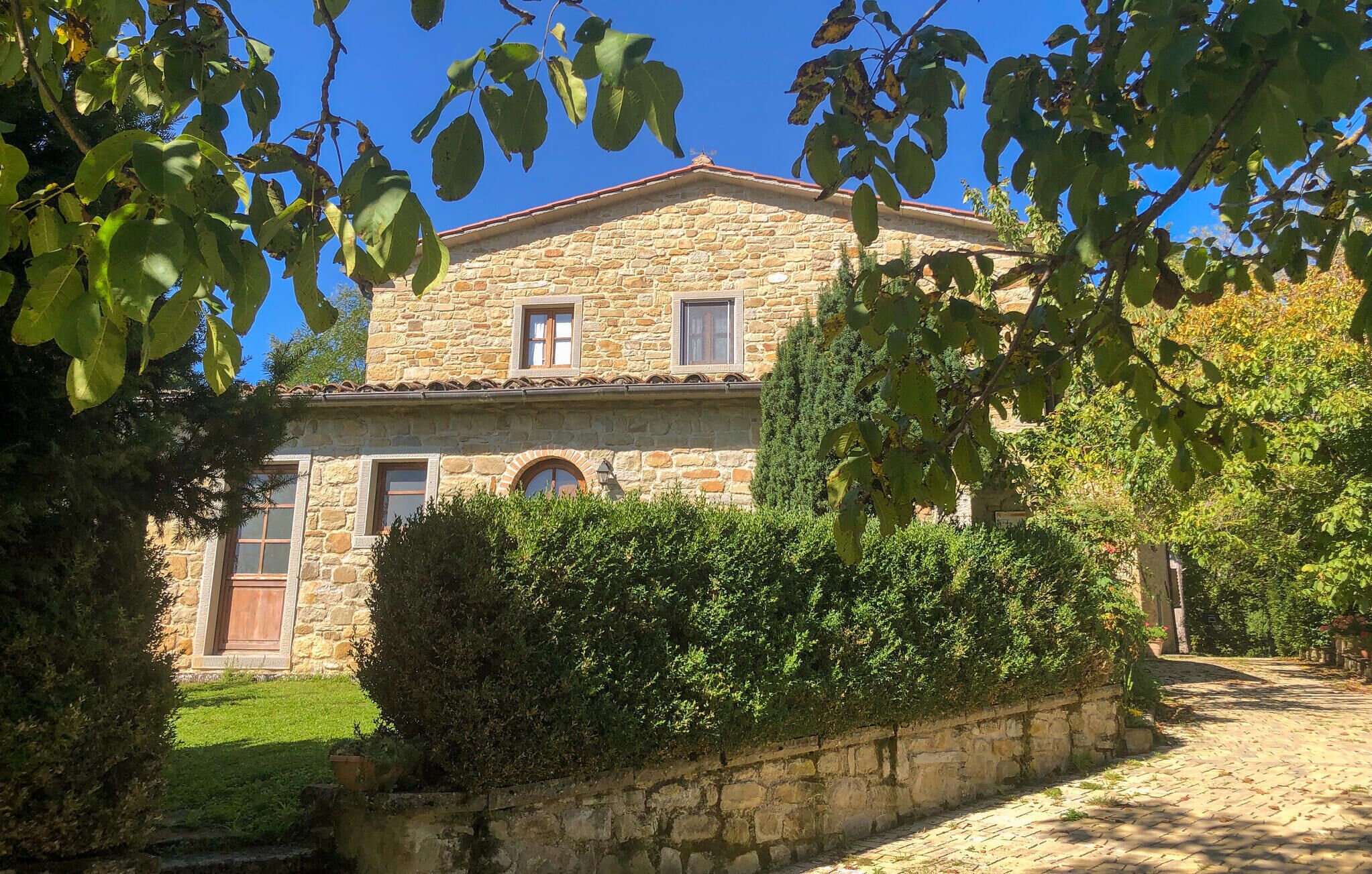 A stone building with a tiled roof, a window with shutters, and a door.