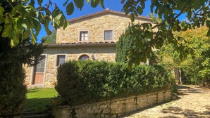 Un edificio de piedra con techo de tejas, una ventana con contraventanas y una puerta.